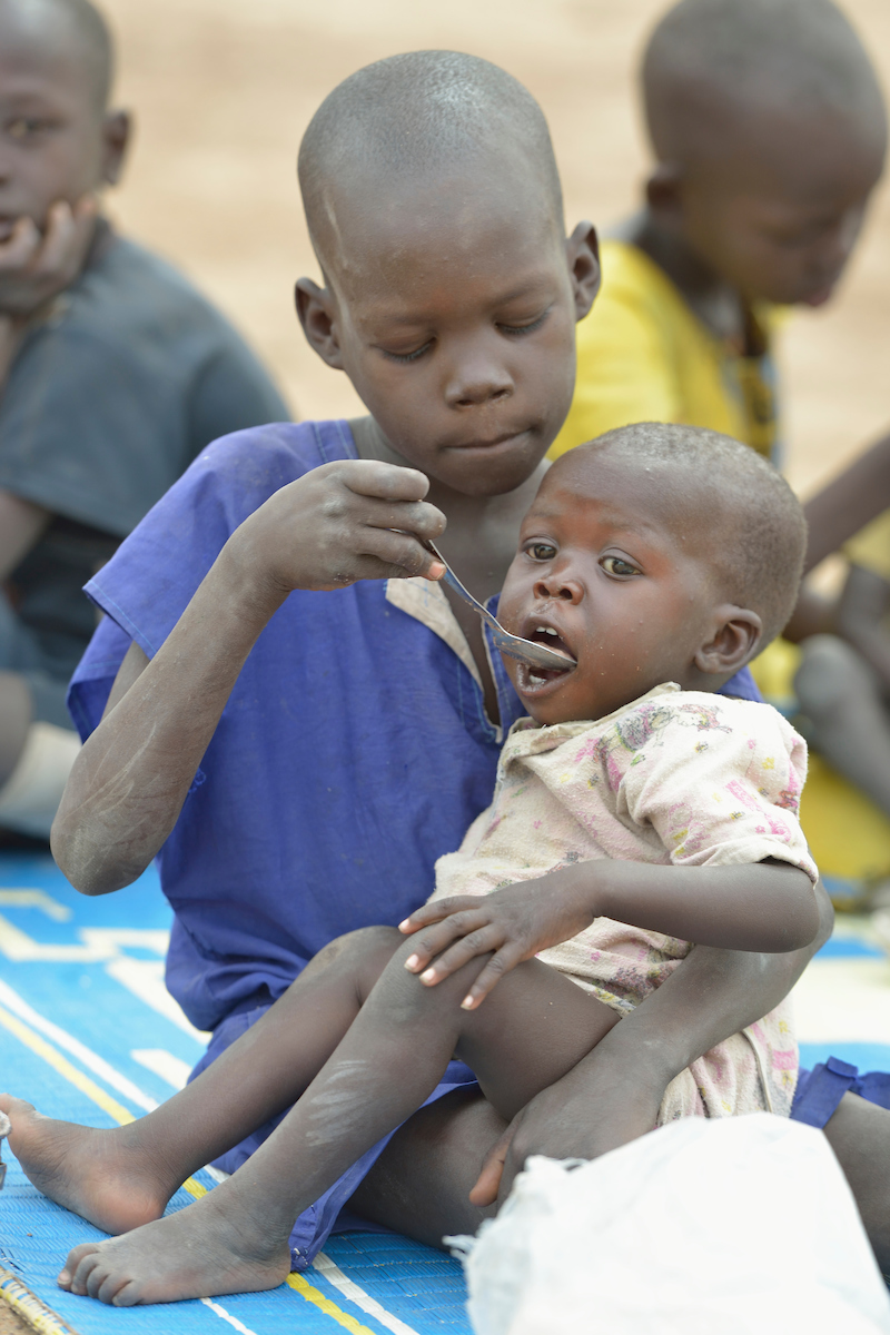 A child feeds their sibling as part of a supplemental feeding program for malnourished children and mothers run by the clinic of the Loreto School in Rumbek, South Sudan. The school is run by the Institute for the Blessed Virgin Mary--the Loreto Sisters--of Ireland.